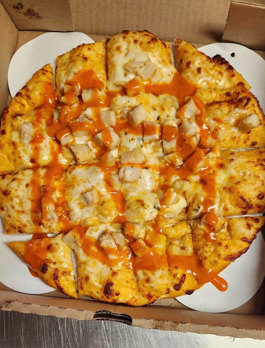 Buffalo chicken pizza sliced in an open takeout box