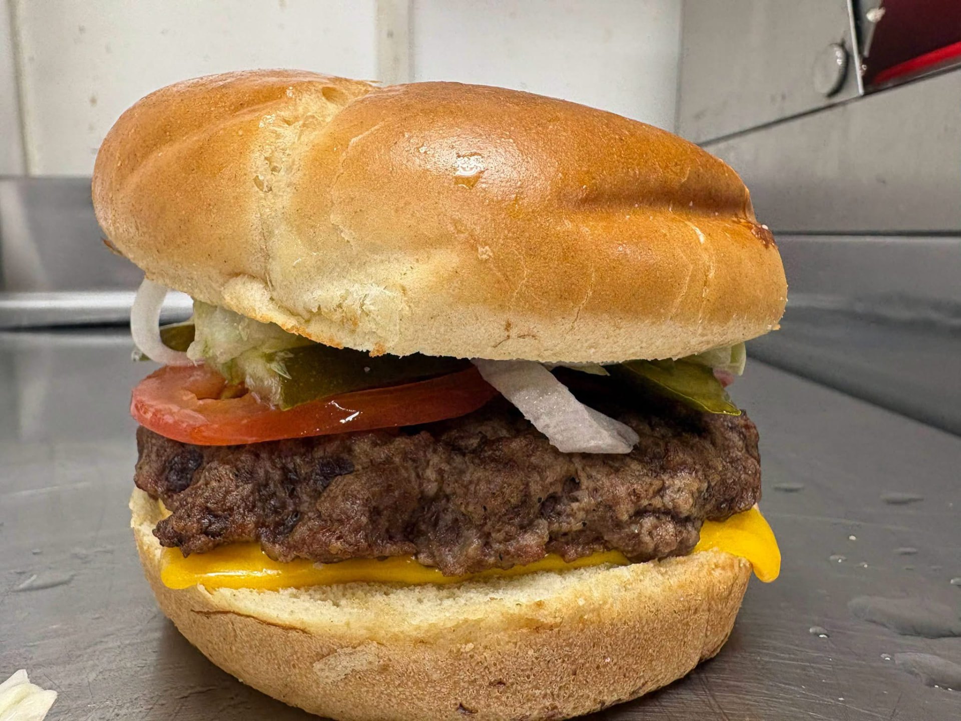 Cheeseburger with melted cheese, tomato, onion, pickles and lettuce on a soft bun