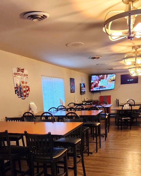 High-top wooden tables with black stools in the dining room, under caged light fixtures