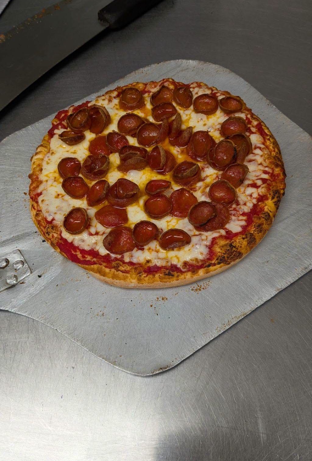 Pepperoni pizza resting on a metal pizza peel